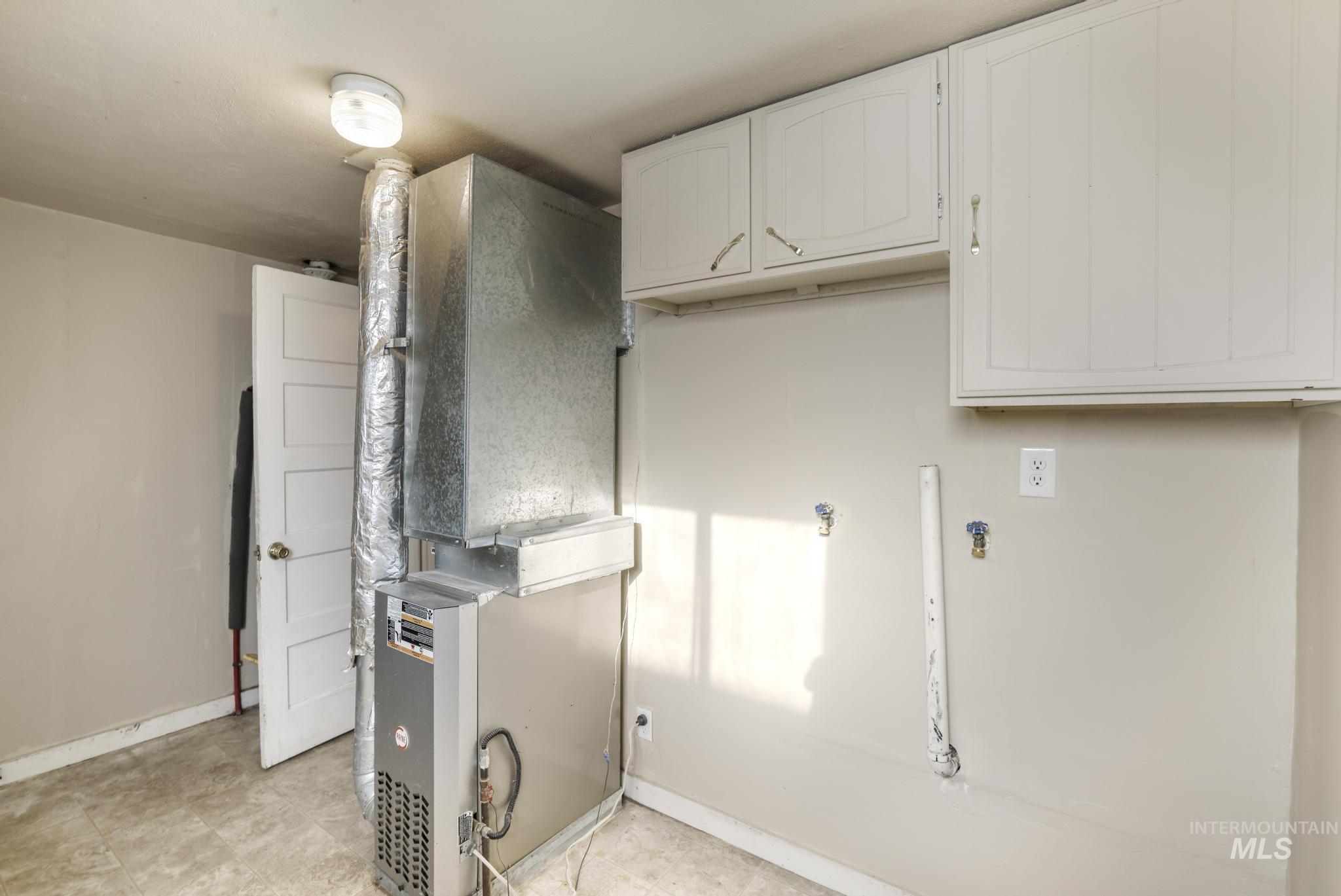 Washroom with heating unit, cabinet space, and hookup for a washing machine