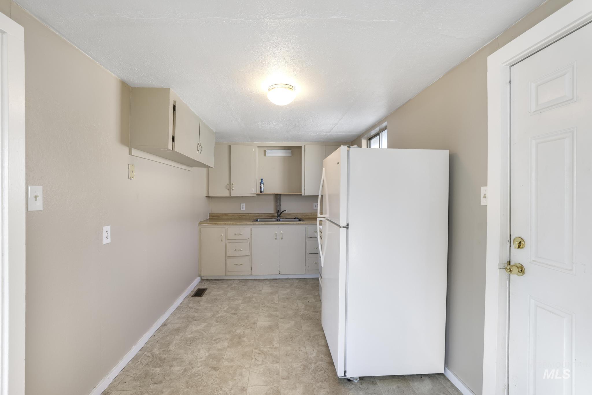 Kitchen with freestanding refrigerator, light countertops, and cream cabinetry