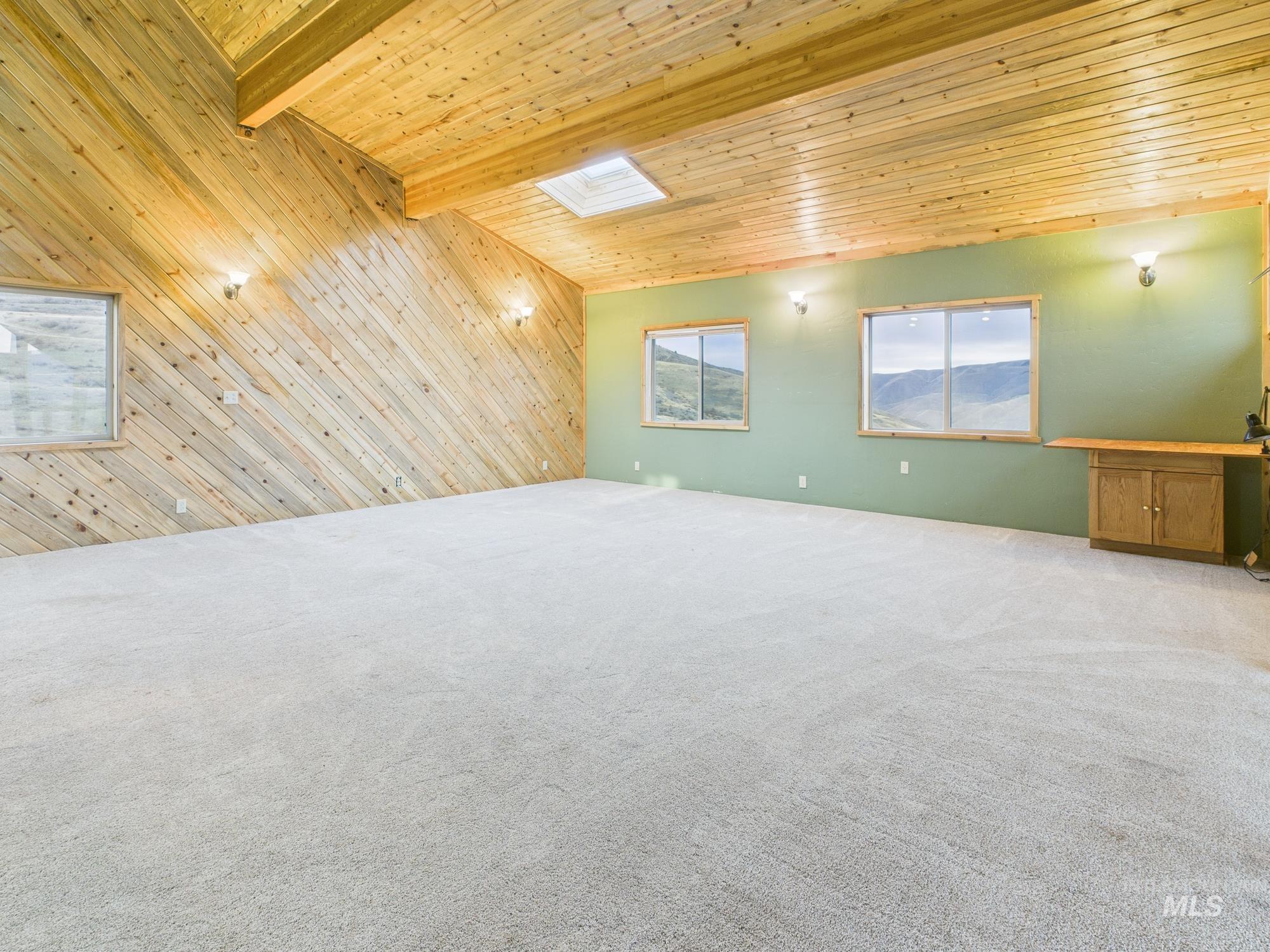 Master room with wood walls, a wooden ceiling with exposed beams, light carpet, and an accent wall