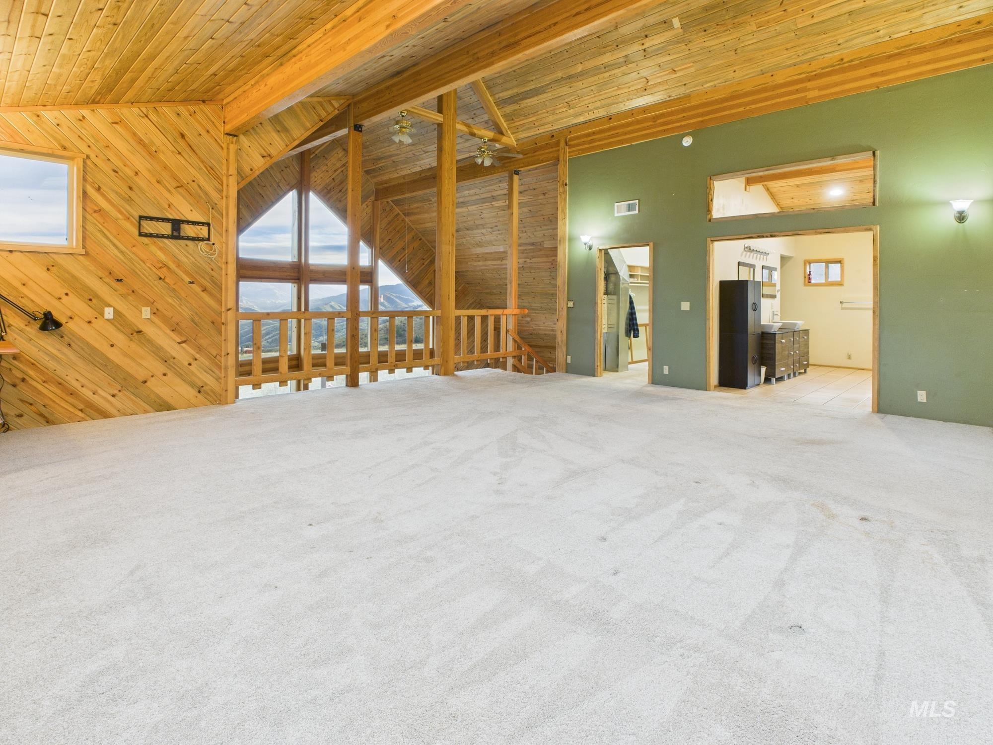 Master room with wood walls, wood ceiling, light carpet, and lofted ceiling