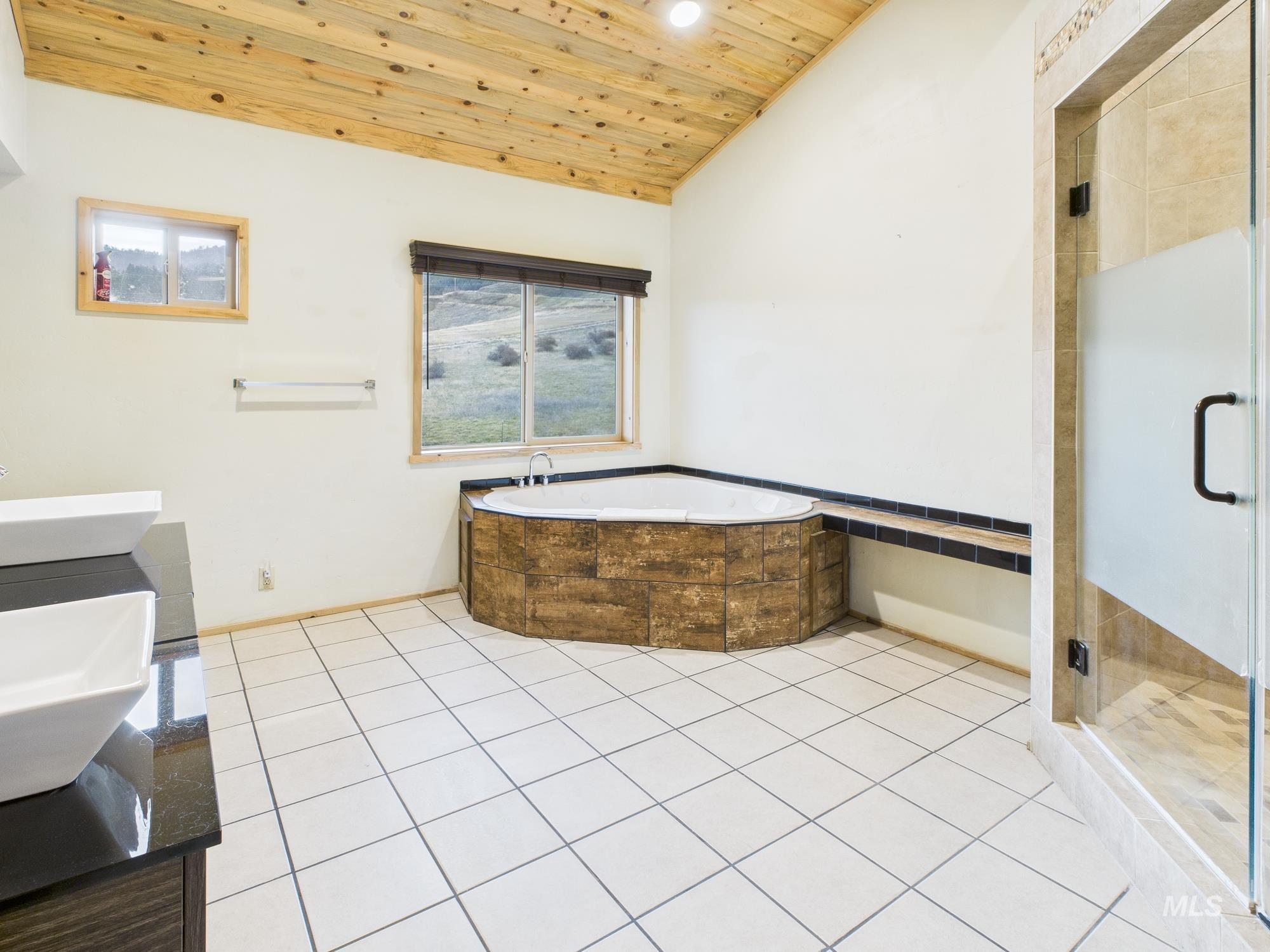 Full bath with wood ceiling, vaulted ceiling, a stall shower, a bath, and light tile patterned floors
