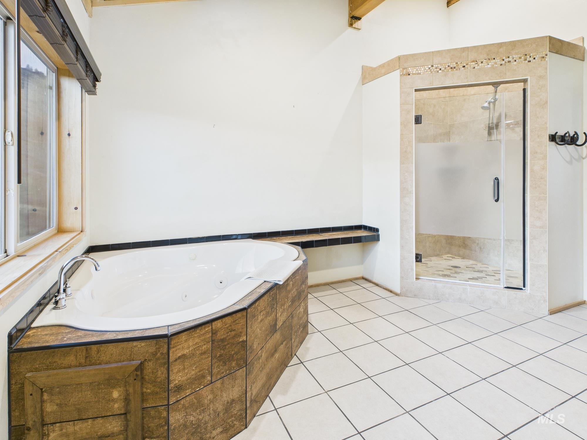 Bathroom with a whirlpool tub, a stall shower, and light tile patterned floors