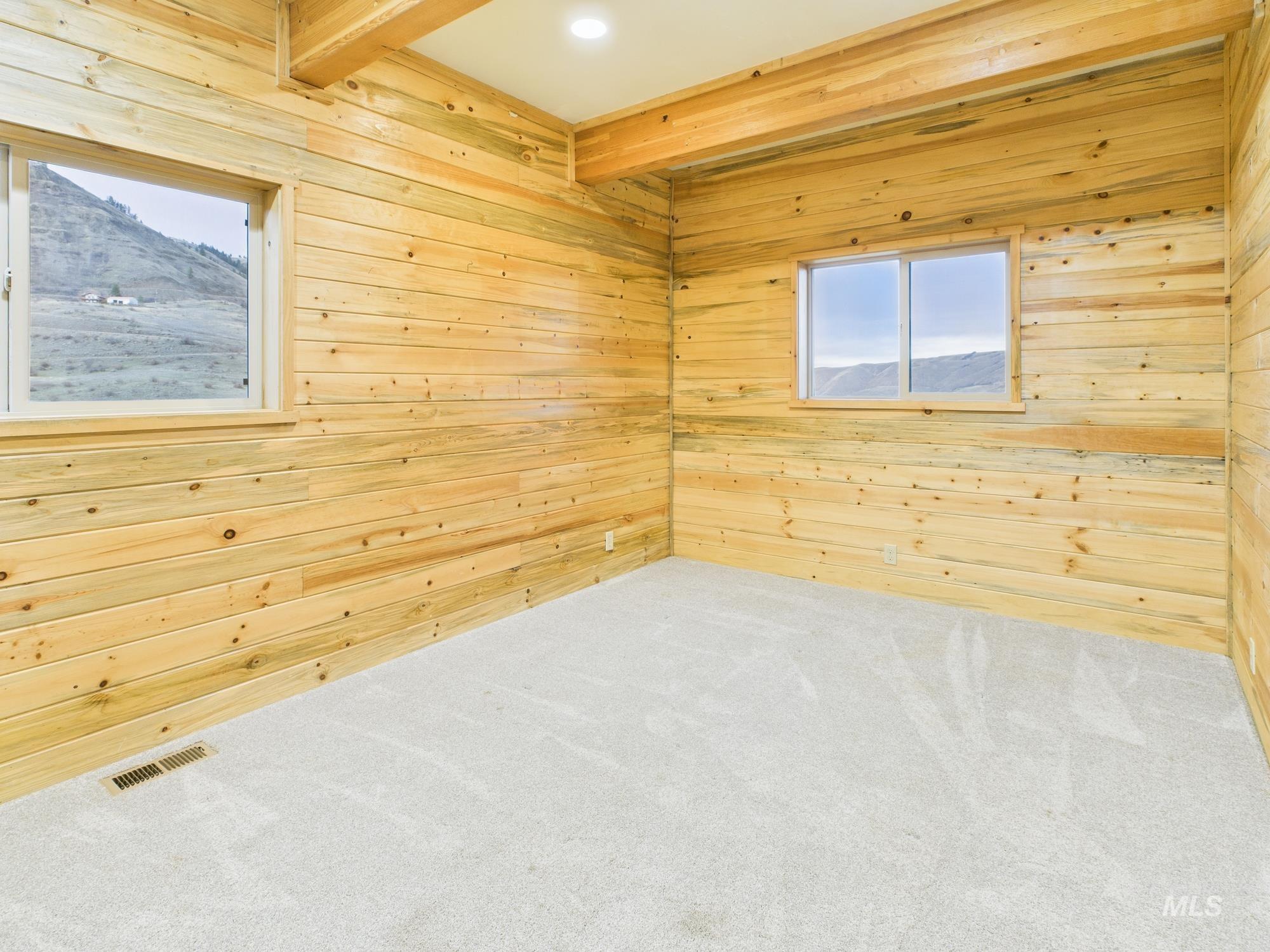 Carpeted empty room featuring wooden walls, beam ceiling, and recessed lighting