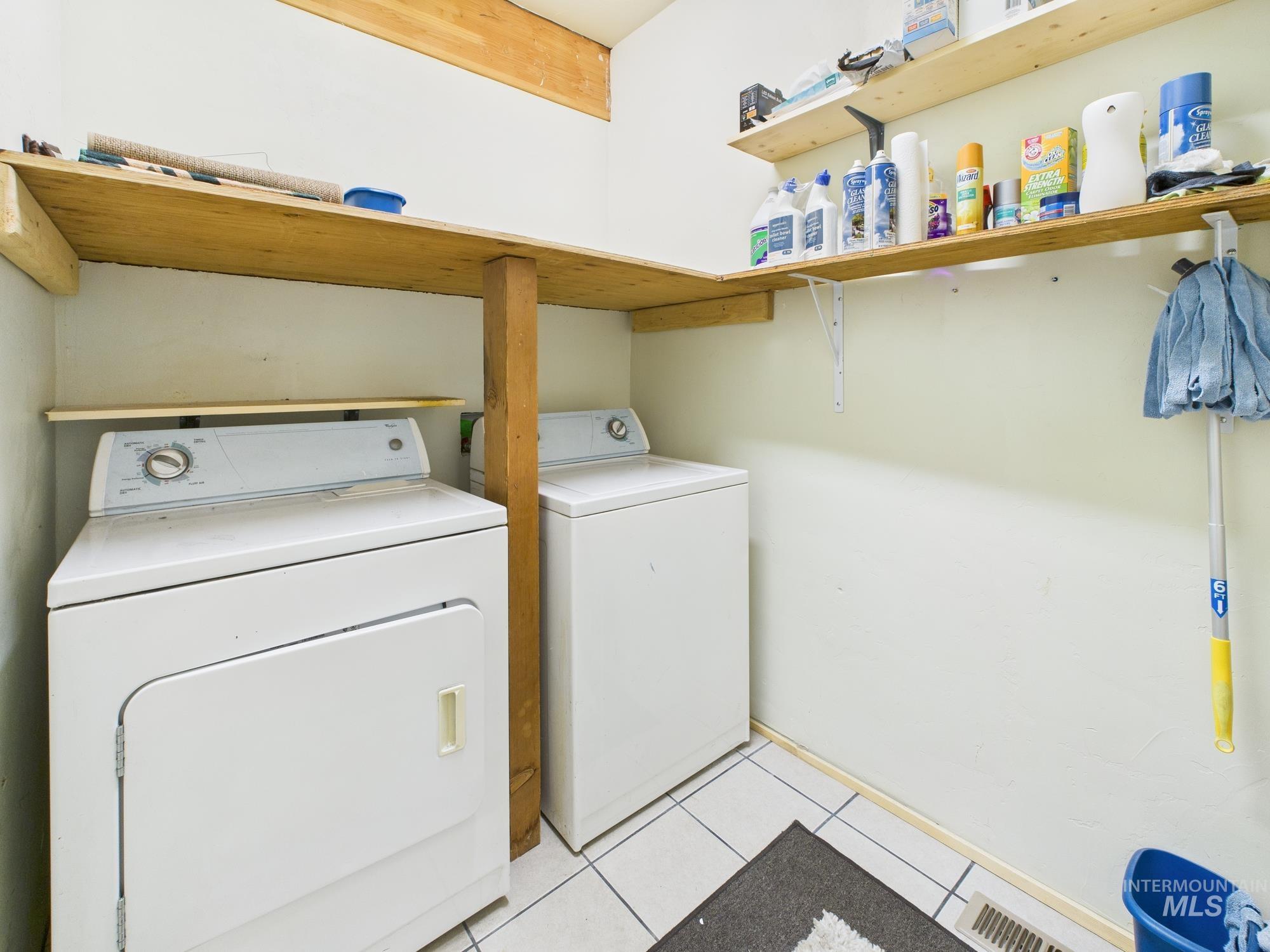 Laundry room with separate washer and dryer and light tile patterned floors