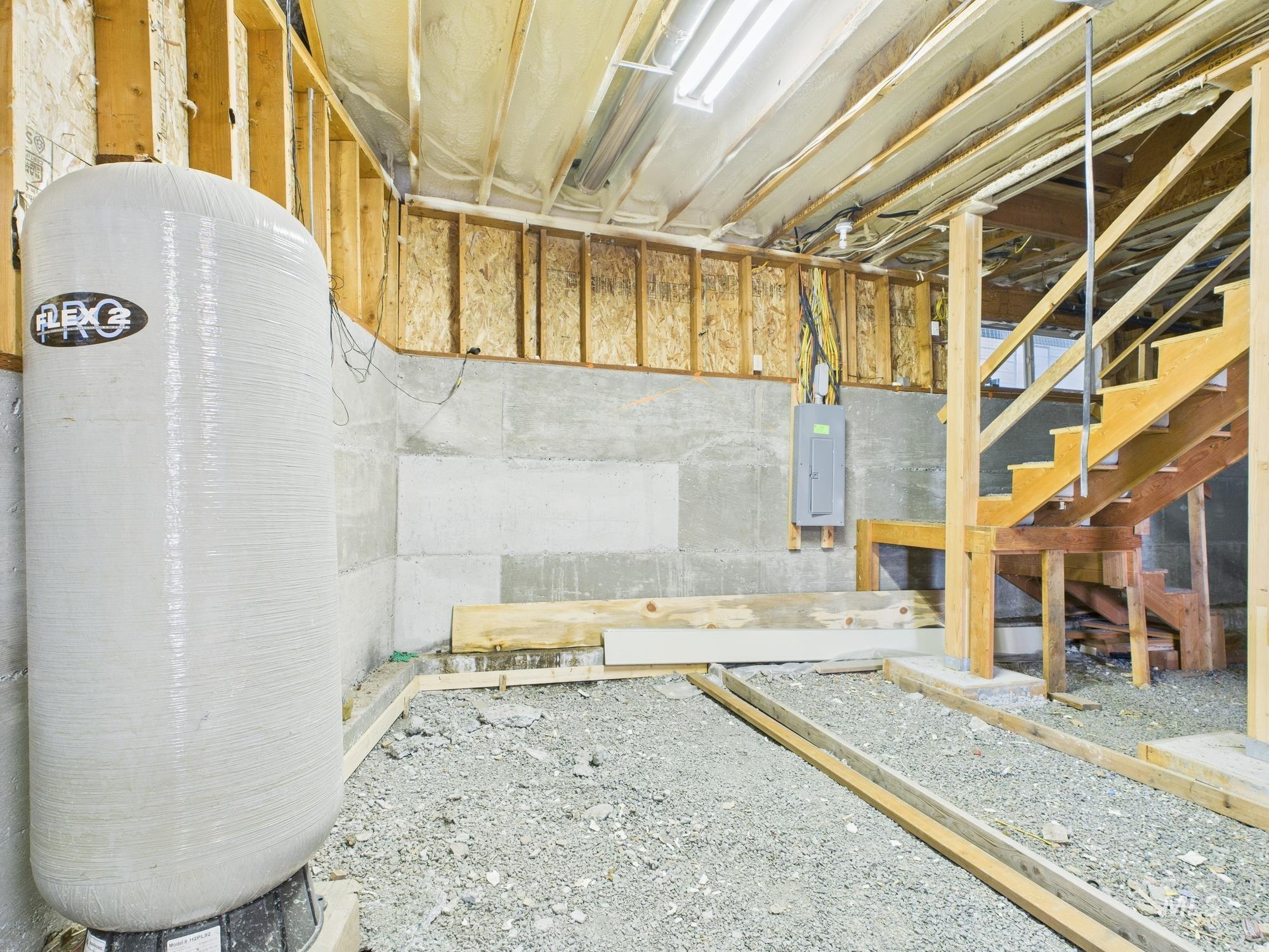Below grade area featuring a water pressure tank, stairway, and electric panel