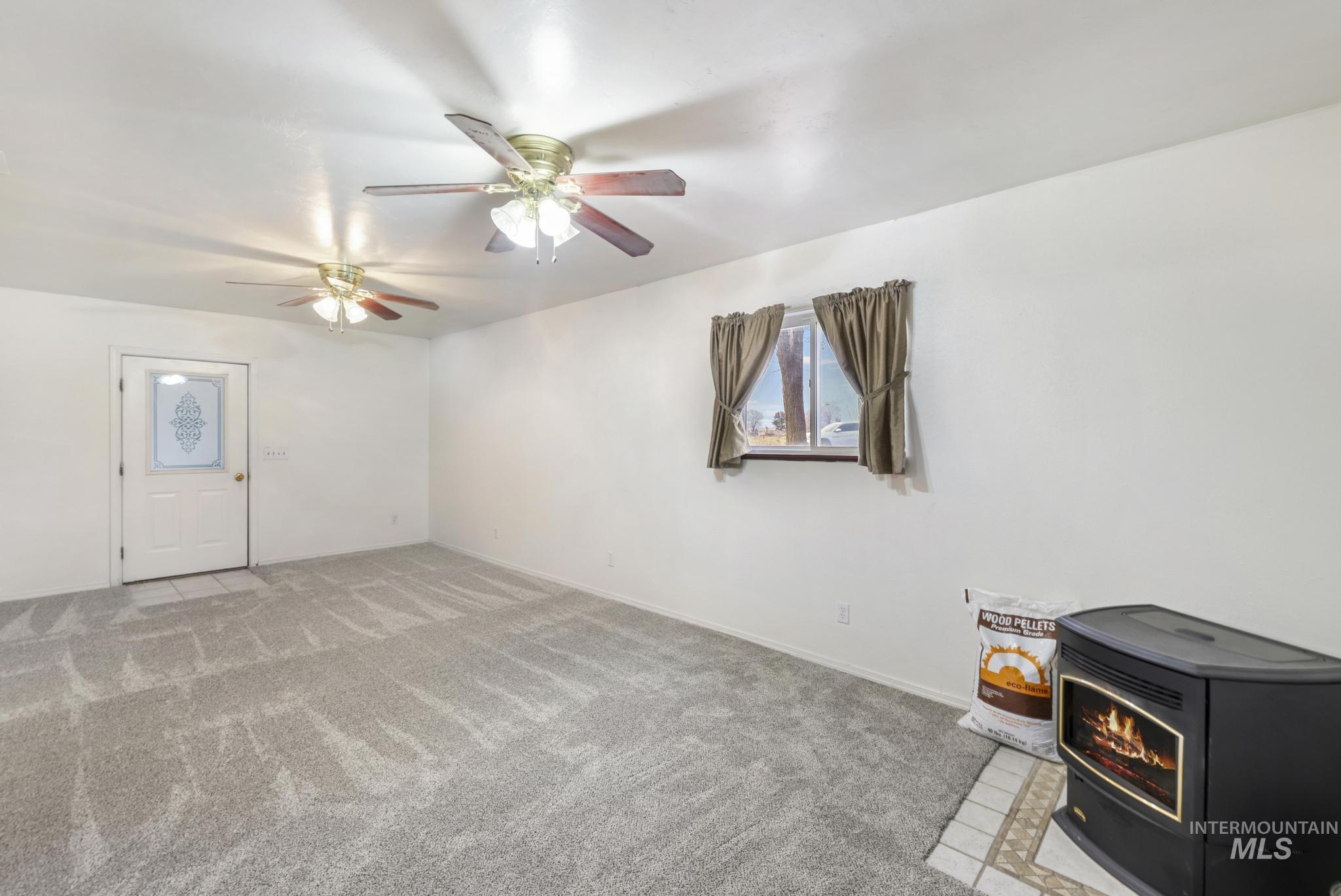 Carpeted living room featuring a wood stove and ceiling fan