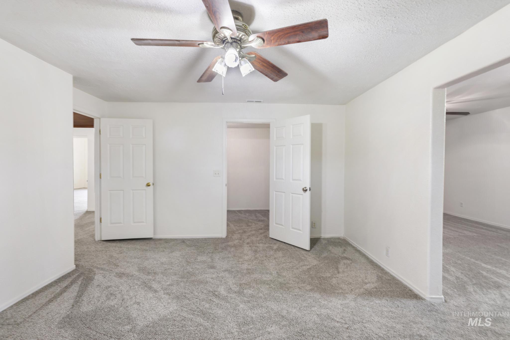 Unfurnished bedroom featuring light colored carpet, ceiling fan, and a textured ceiling