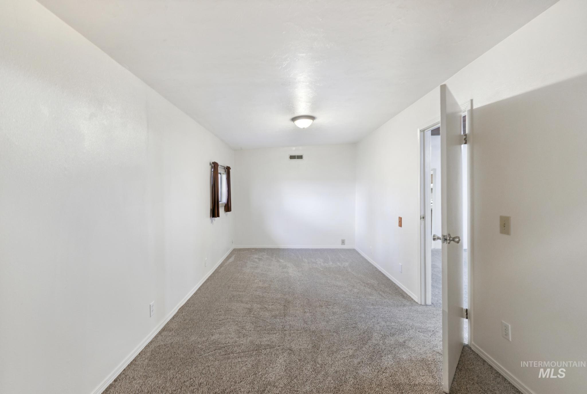 Spare room featuring carpet and baseboards