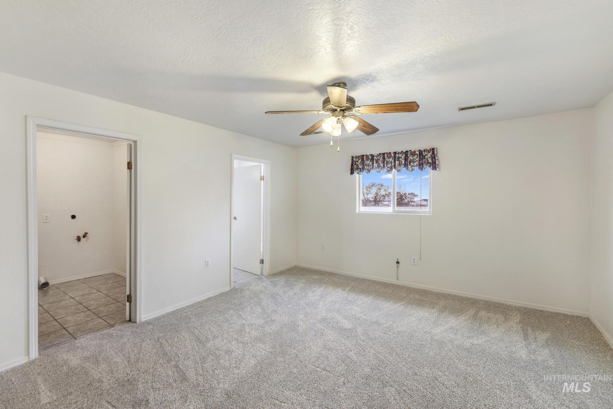 Unfurnished bedroom with light carpet, a textured ceiling, and ceiling fan