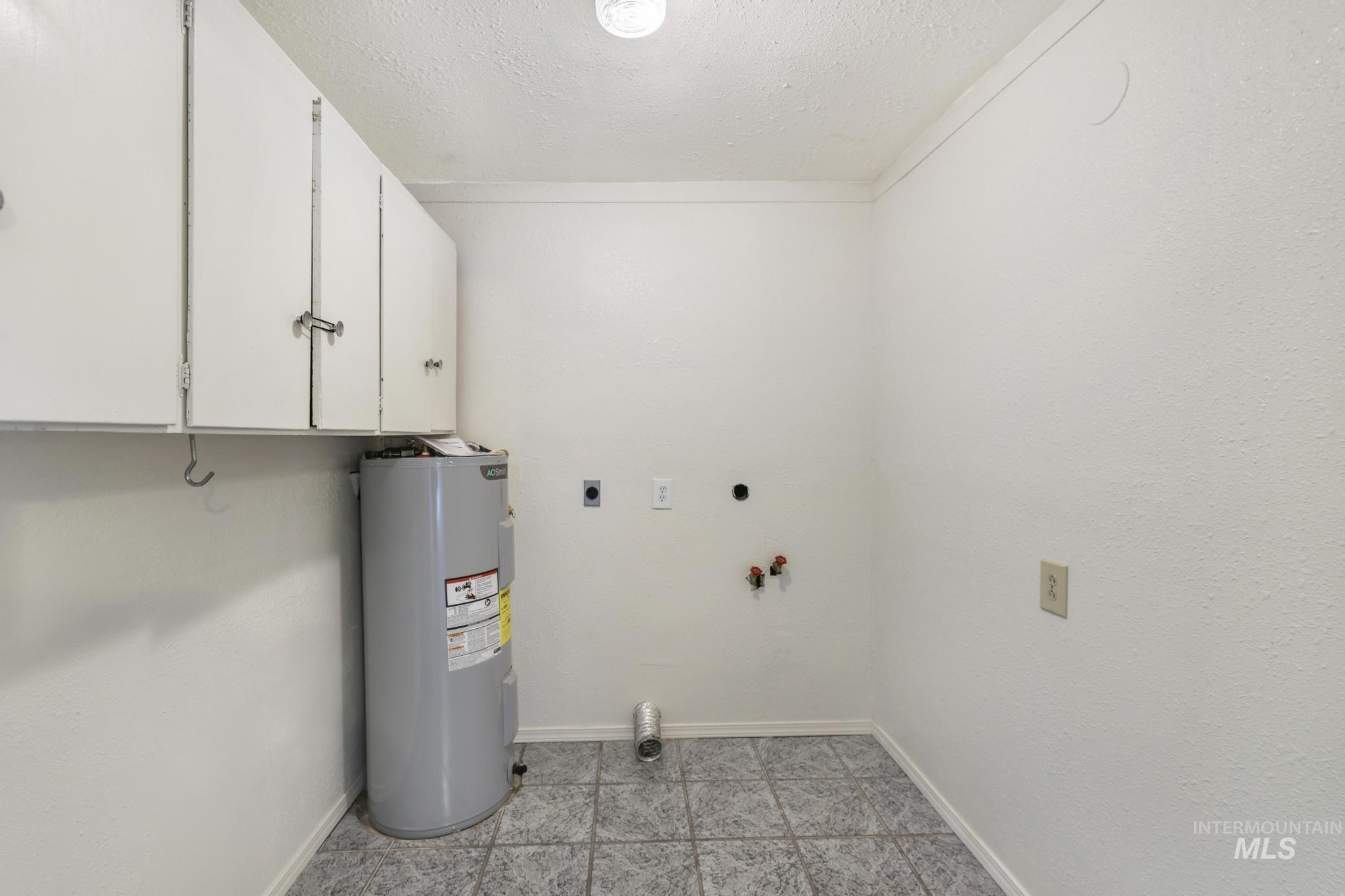 Laundry room with electric water heater, a textured ceiling, washer hookup, cabinet space, and electric dryer hookup