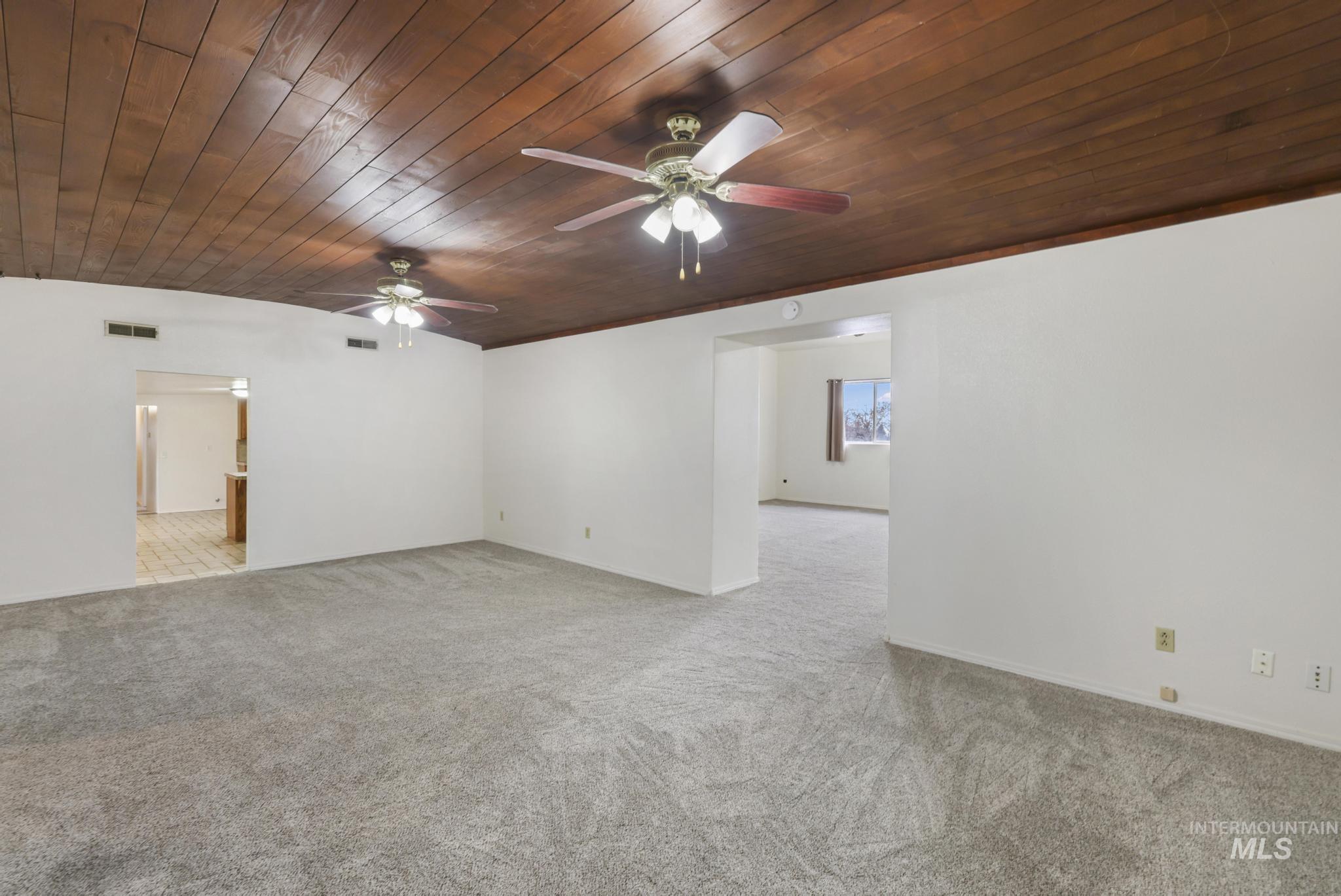 Empty room with wood ceiling, light colored carpet, and ceiling fan