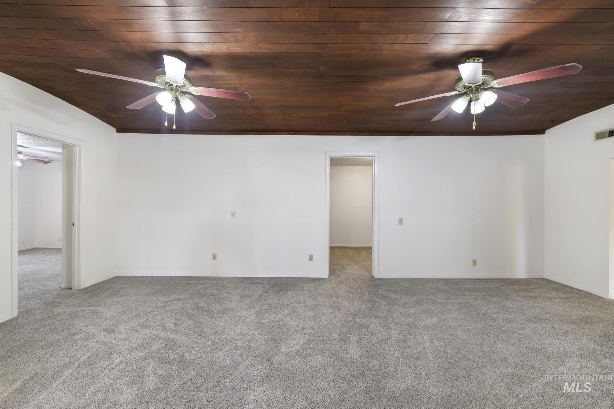 Spare room with a ceiling fan, light carpet, and wooden ceiling