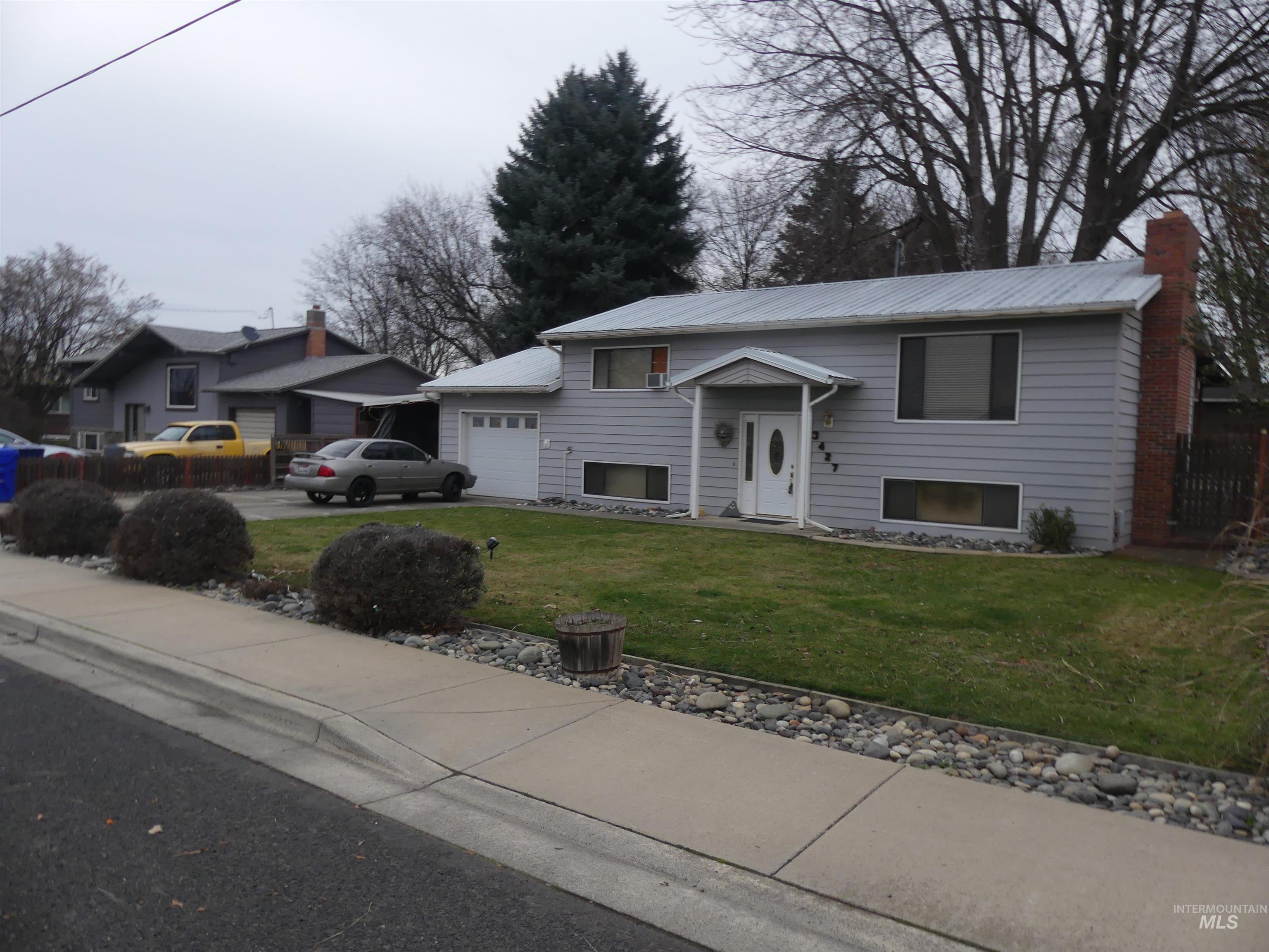 Raised ranch with a front yard, driveway, a garage, and a chimney