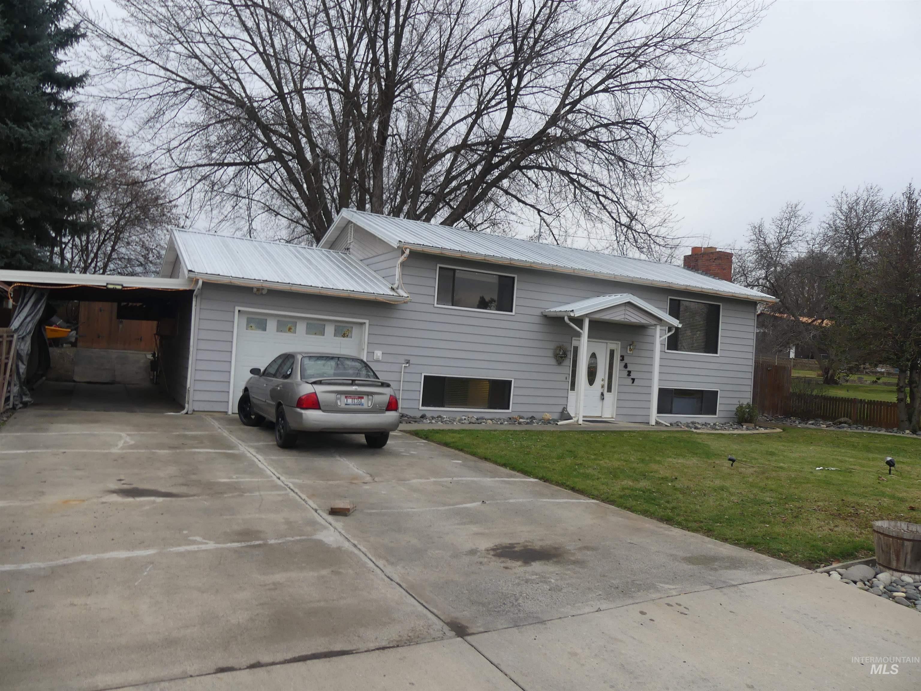 Split foyer home with a front lawn, driveway, a chimney, a carport, and an attached garage