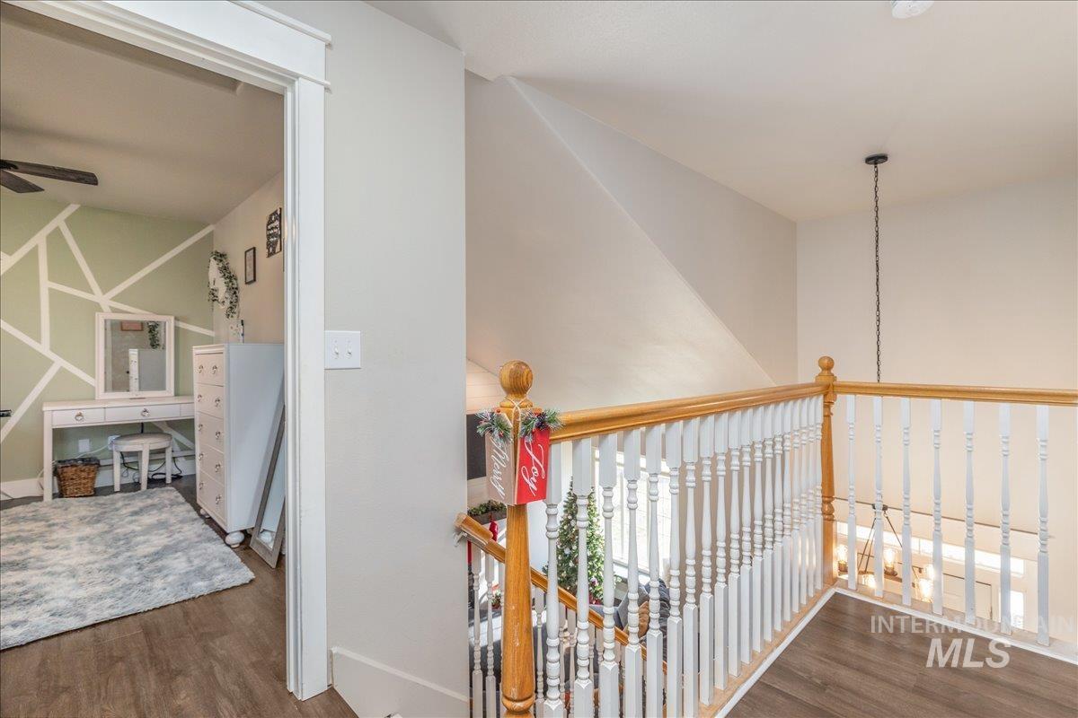 Hallway with dark wood finished floors, an upstairs landing, and a chandelier