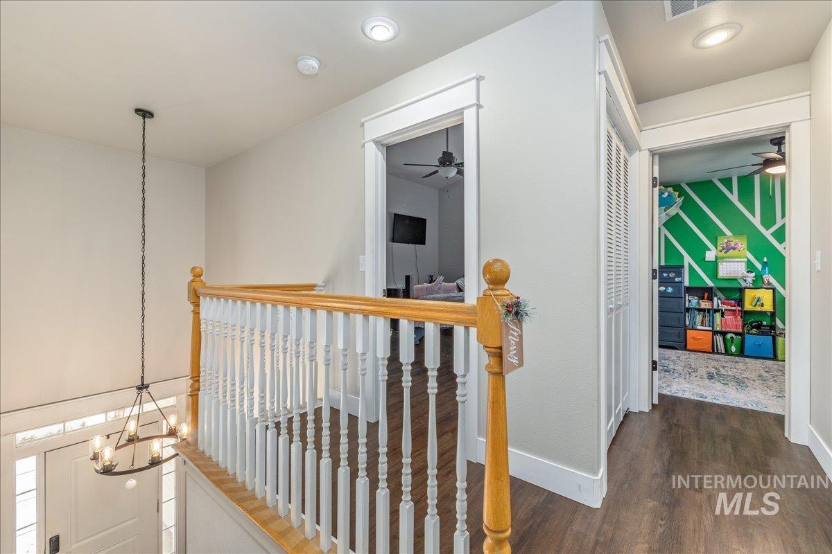 Hallway featuring a chandelier, dark wood finished floors, and an upstairs landing