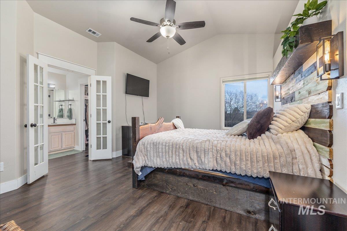 Bedroom with french doors, lofted ceiling, dark wood-style flooring, and a ceiling fan