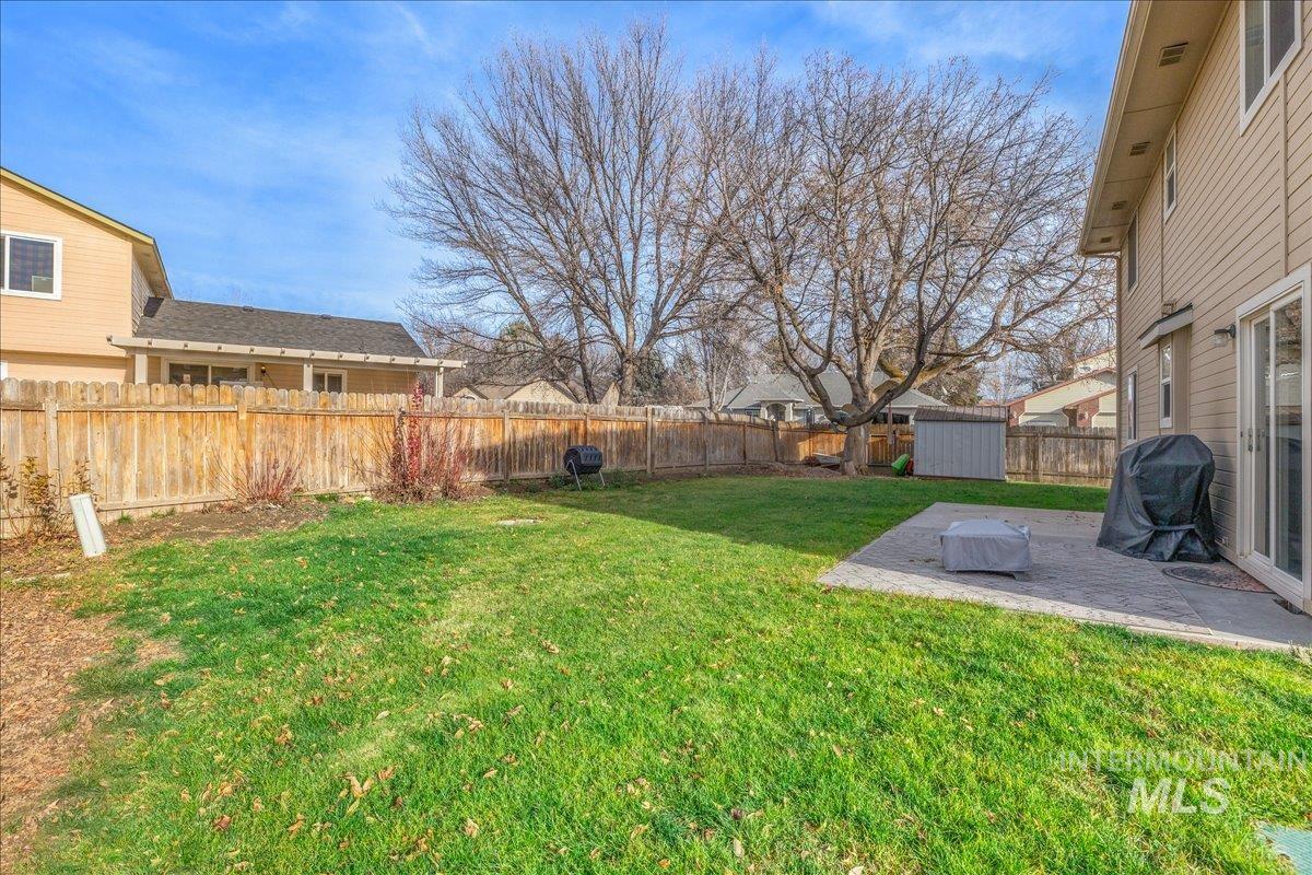 Fenced backyard with a patio area, a shed, and a residential view