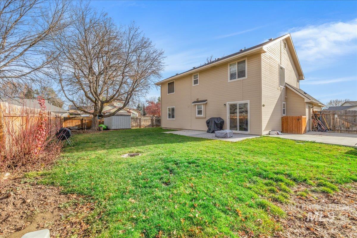 Rear view of property with a fenced backyard, a patio, and a shed