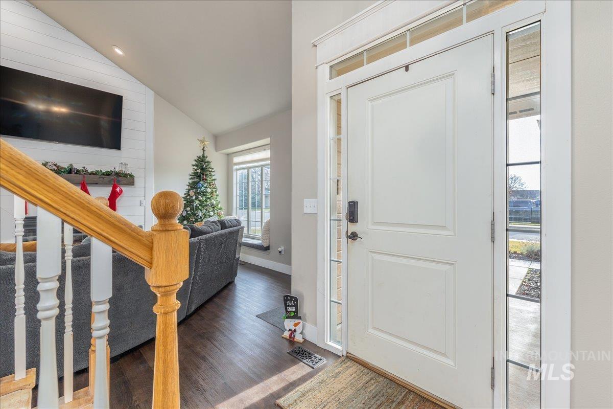 Entryway with lofted ceiling, stairs, and wood finished floors