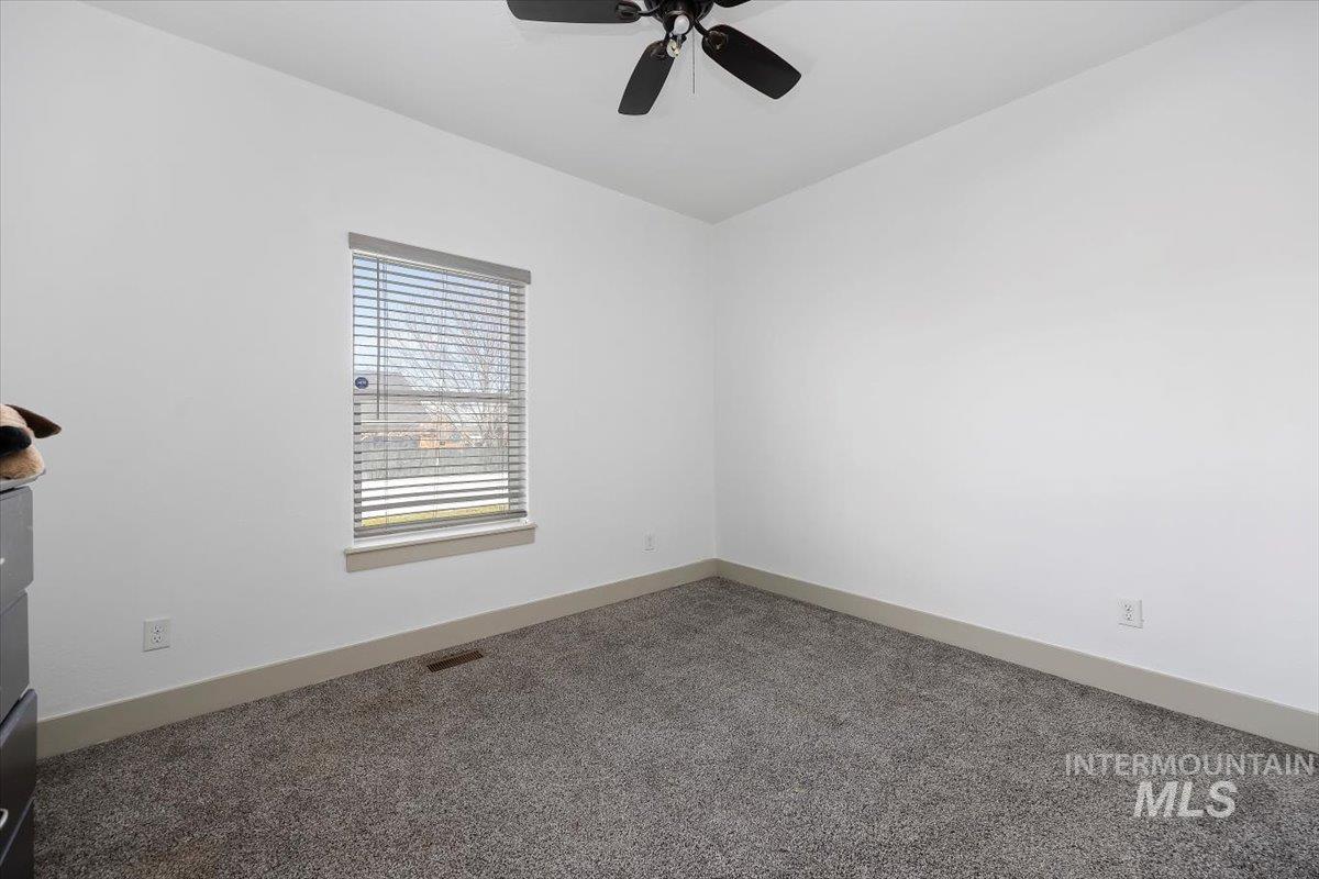 Carpeted empty room featuring baseboards and a ceiling fan