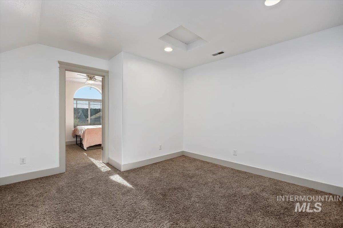 Empty room with attic access, carpet floors, lofted ceiling, and recessed lighting
