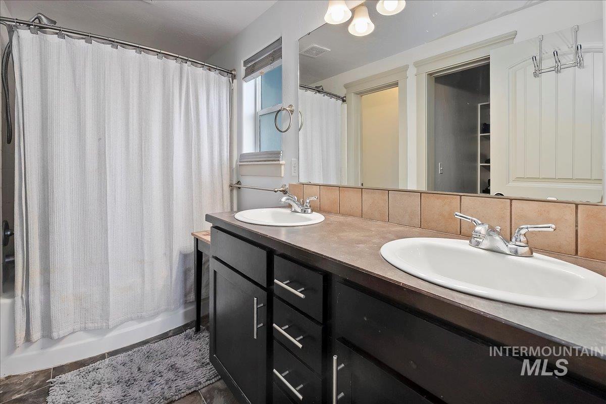 Bathroom with shower / tub combo, double vanity, and backsplash