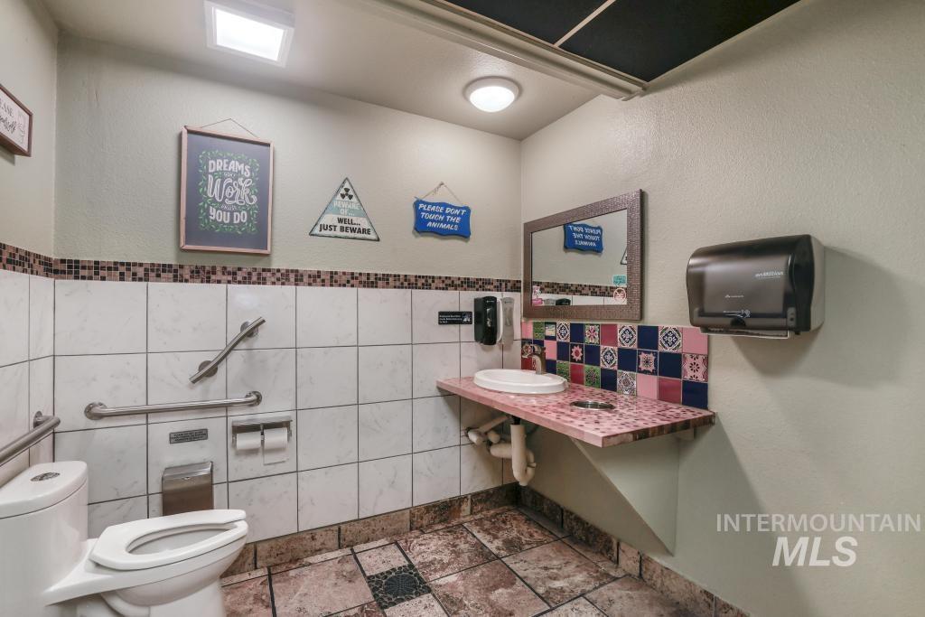 Half bathroom featuring a textured wall and tile walls