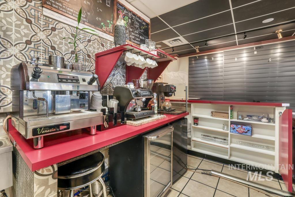 Kitchen with light tile patterned floors, wine cooler, and black refrigerator