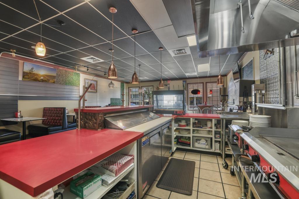 Kitchen with light tile patterned floors, ventilation hood, decorative light fixtures, and open floor plan