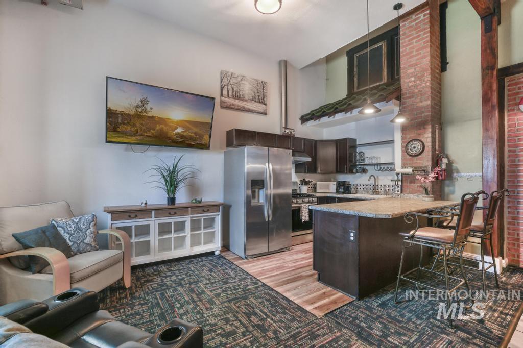 Kitchen featuring dark brown cabinets, stainless steel appliances, light wood-type flooring, light countertops, and a breakfast bar area