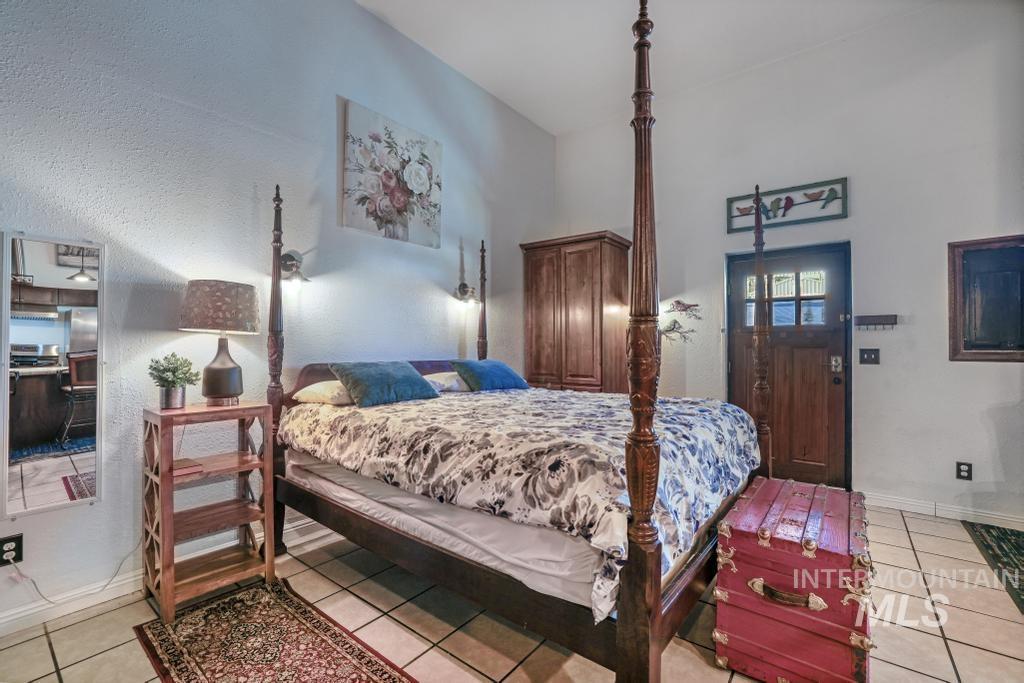 Bedroom featuring light tile patterned floors, a textured wall, and a towering ceiling