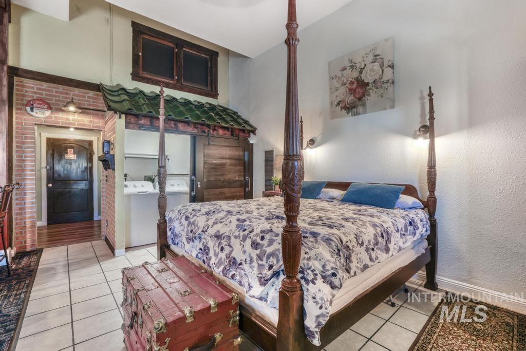 Bedroom featuring light tile patterned floors and washing machine and clothes dryer
