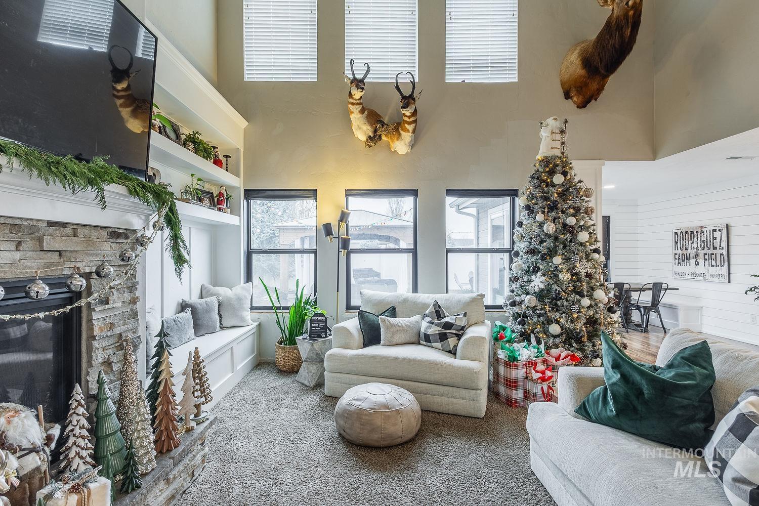 Carpeted living room with a towering ceiling and a stone fireplace