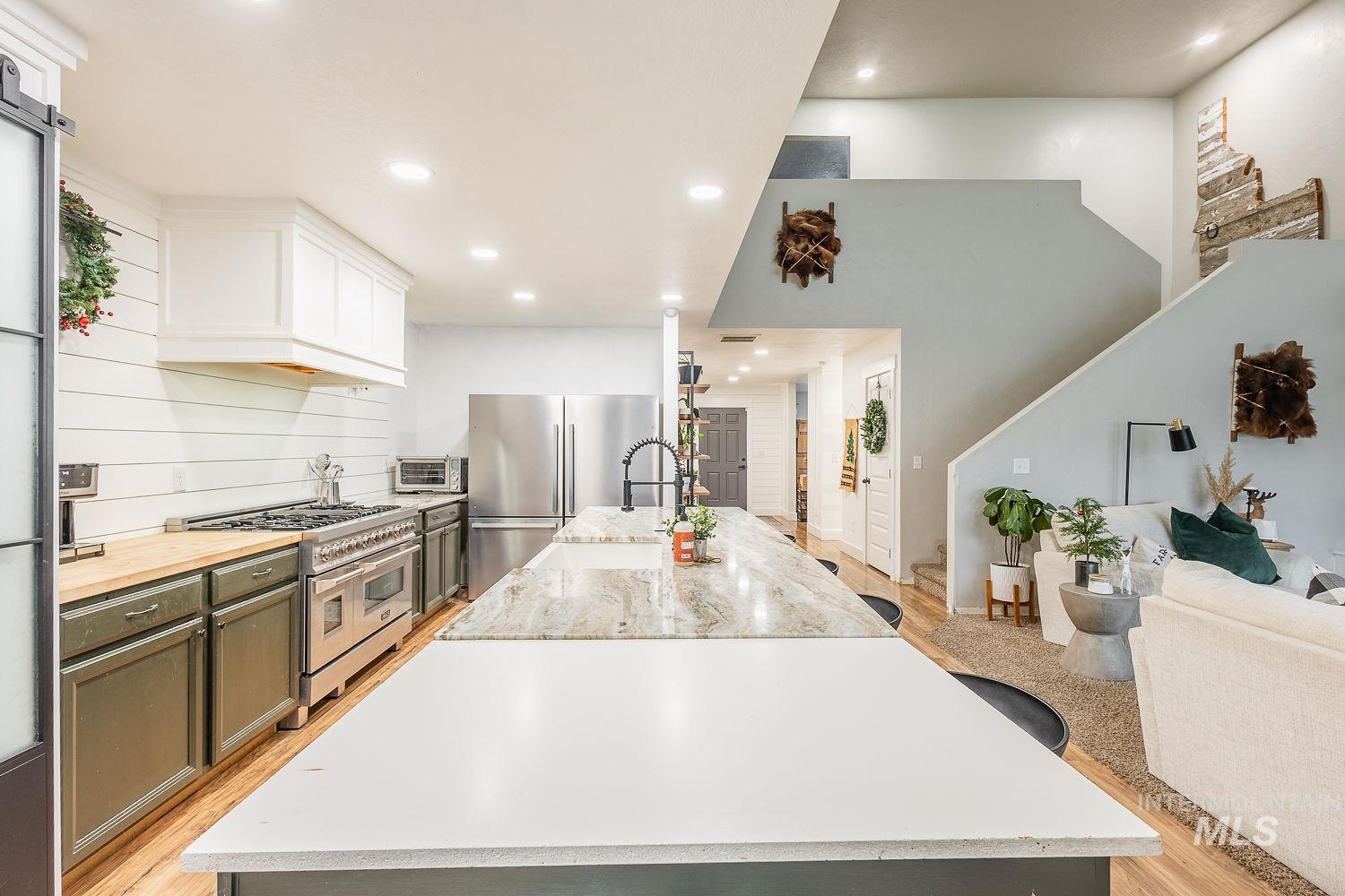 Kitchen with wood counters, stainless steel appliances, a large island, open floor plan, and recessed lighting
