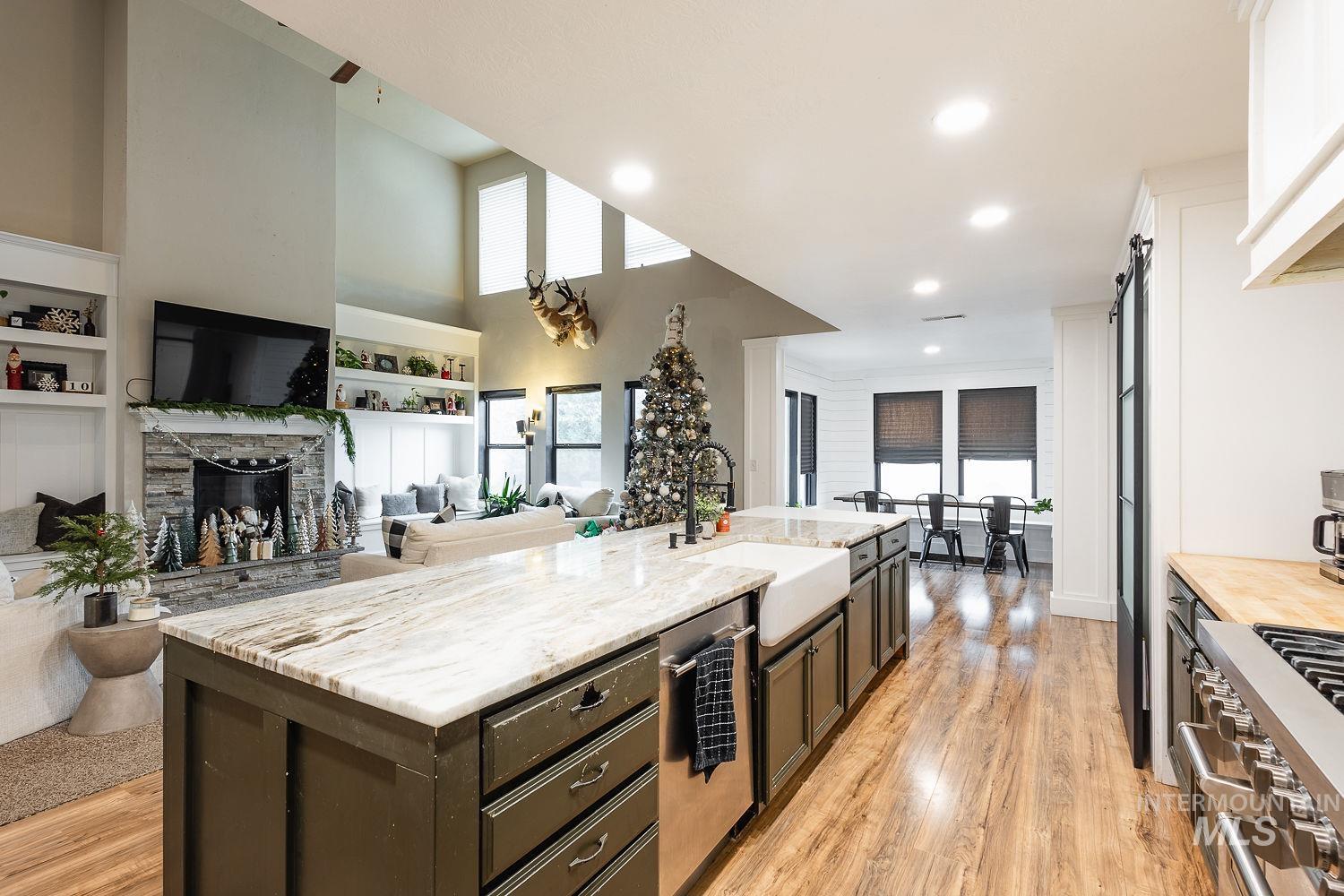 Kitchen with appliances with stainless steel finishes, open floor plan, a stone fireplace, plenty of natural light, and recessed lighting