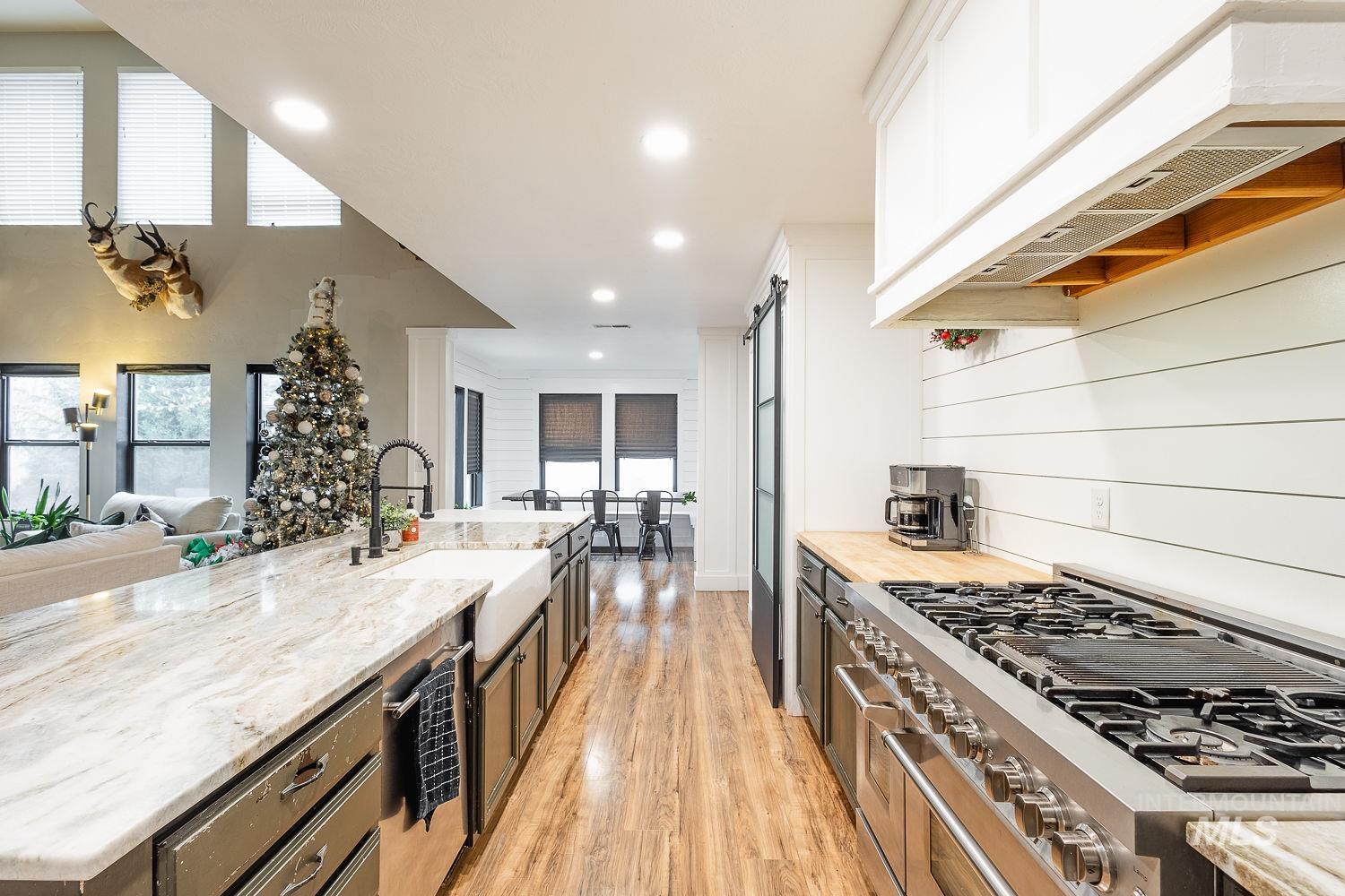 Kitchen featuring stainless steel appliances, light wood finished floors, recessed lighting, open floor plan, and light stone counters
