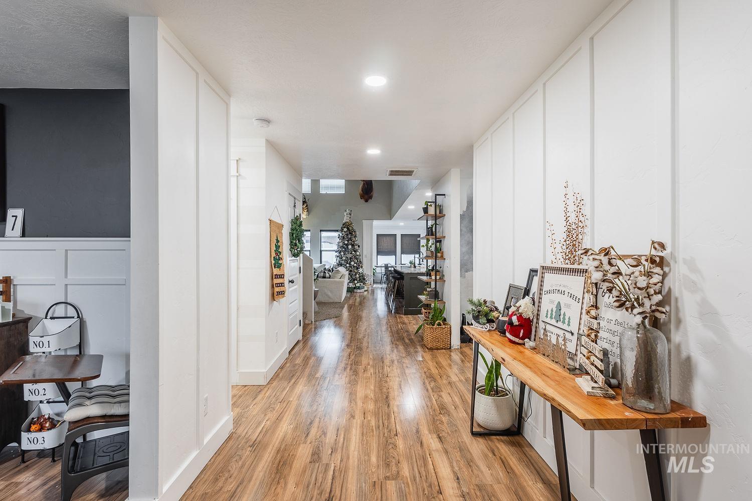 Corridor featuring a decorative wall, light wood-style floors, a wainscoted wall, and recessed lighting