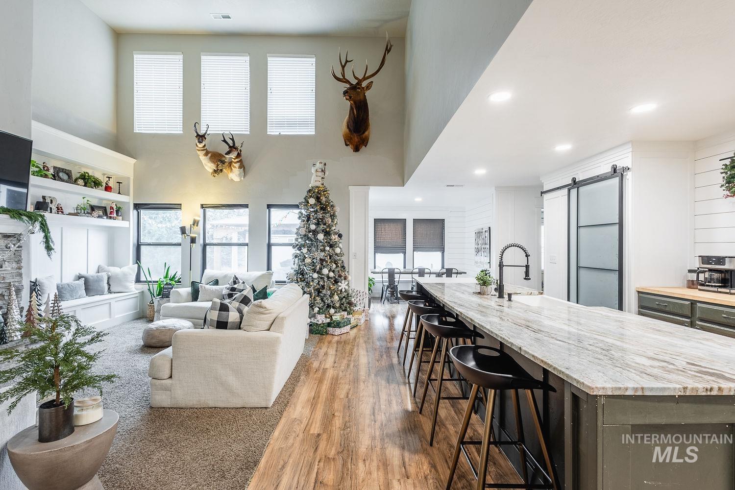 Living room with a barn door, wood finished floors, a high ceiling, and recessed lighting