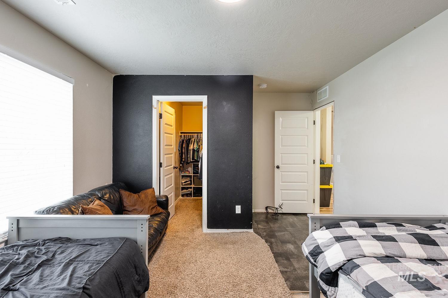 Bedroom featuring a spacious closet, carpet, and a textured ceiling