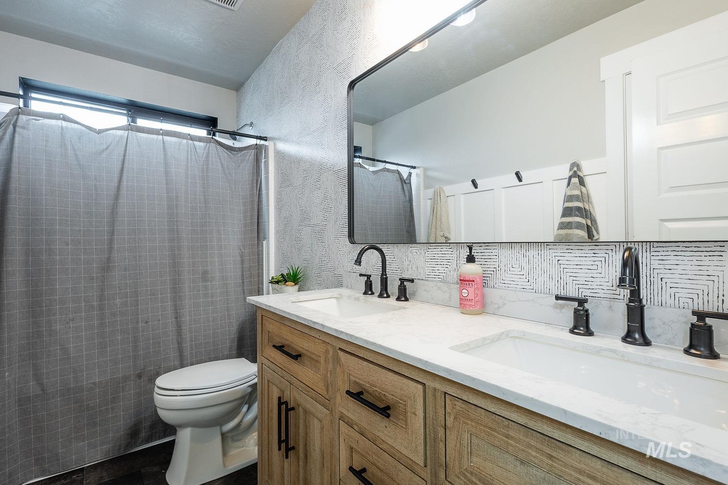 Full bathroom with double vanity, a shower with shower curtain, and a textured wall