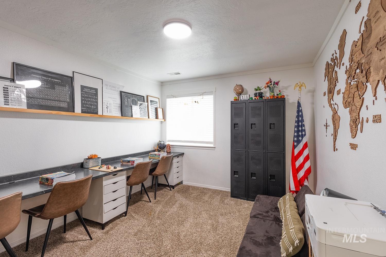 Office with a textured ceiling and light colored carpet