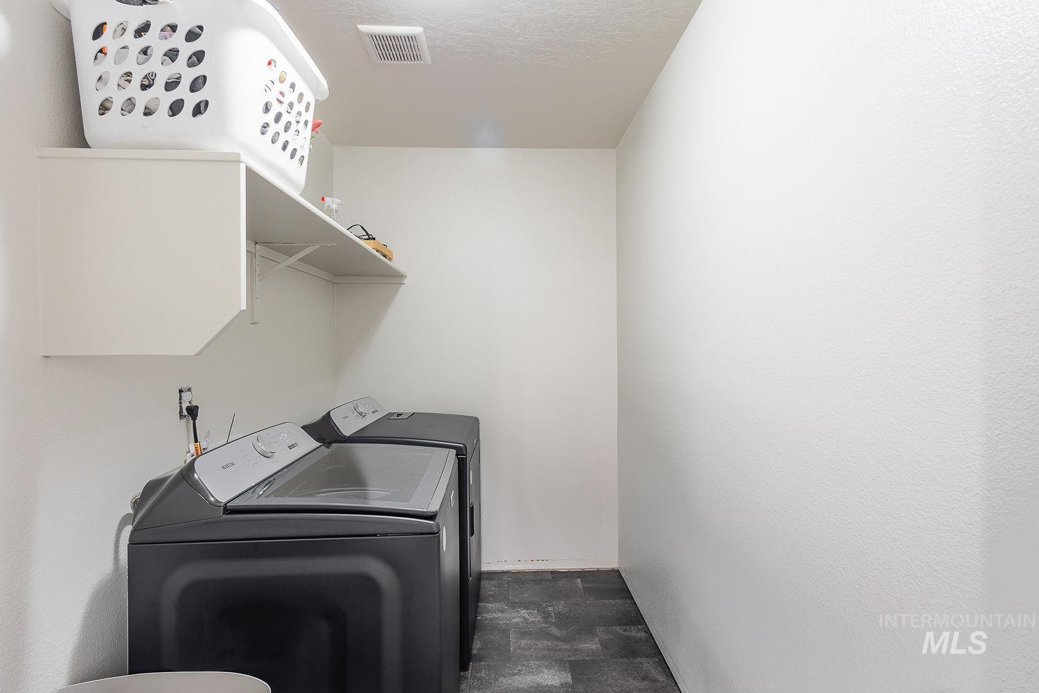 Laundry room with stone finish flooring, independent washer and dryer, and a textured ceiling