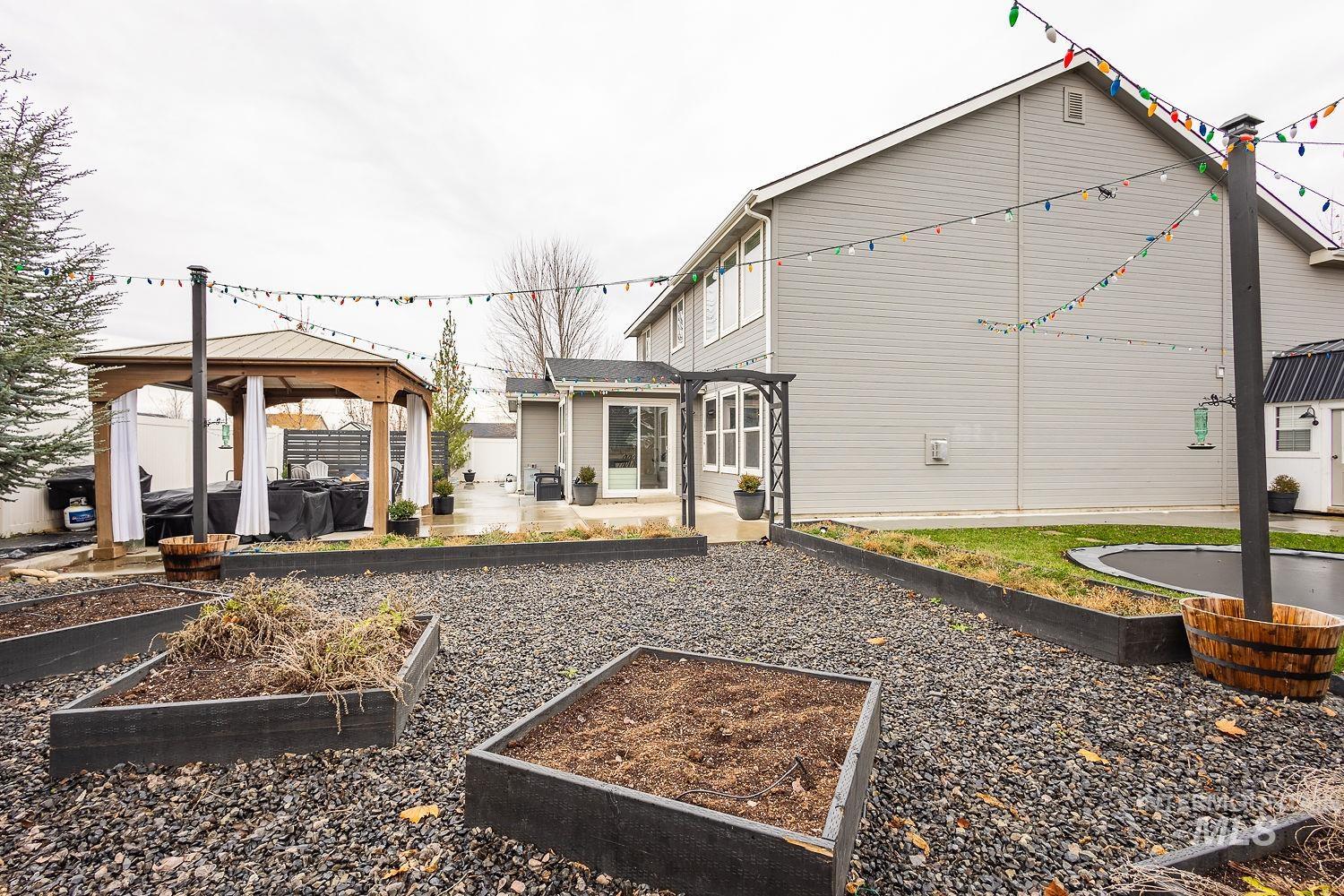 Back of house with a gazebo, a patio area, and a garden
