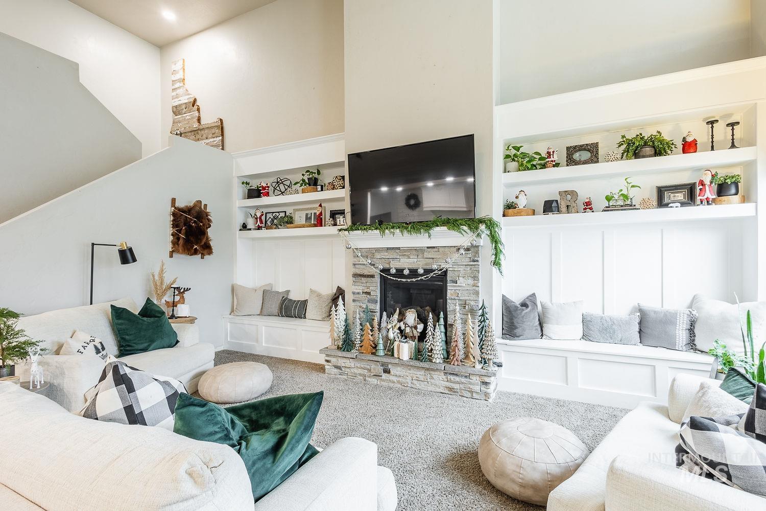 Living area featuring built in features, a stone fireplace, and carpet floors