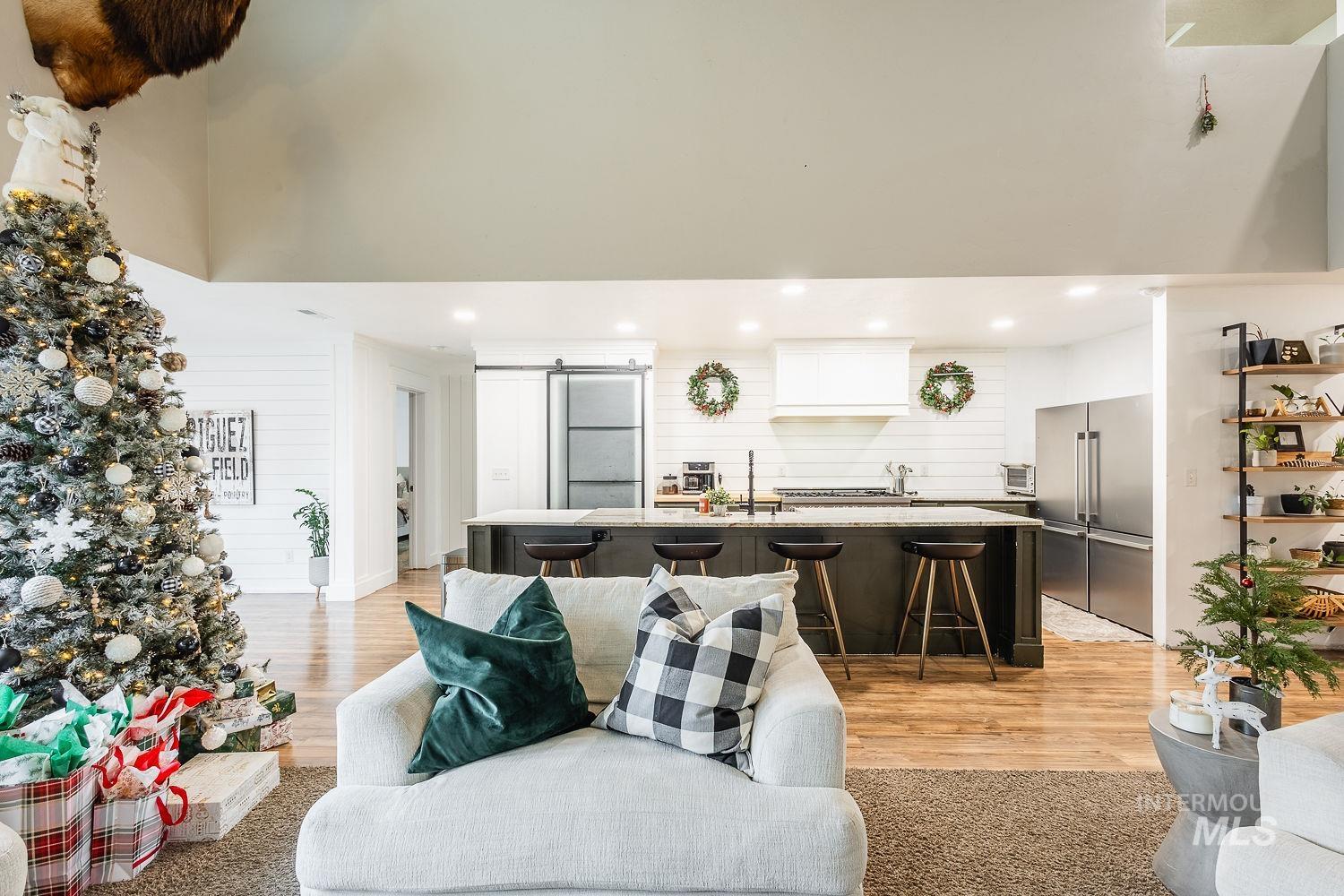 Living room with a barn door, a high ceiling, light wood finished floors, and recessed lighting