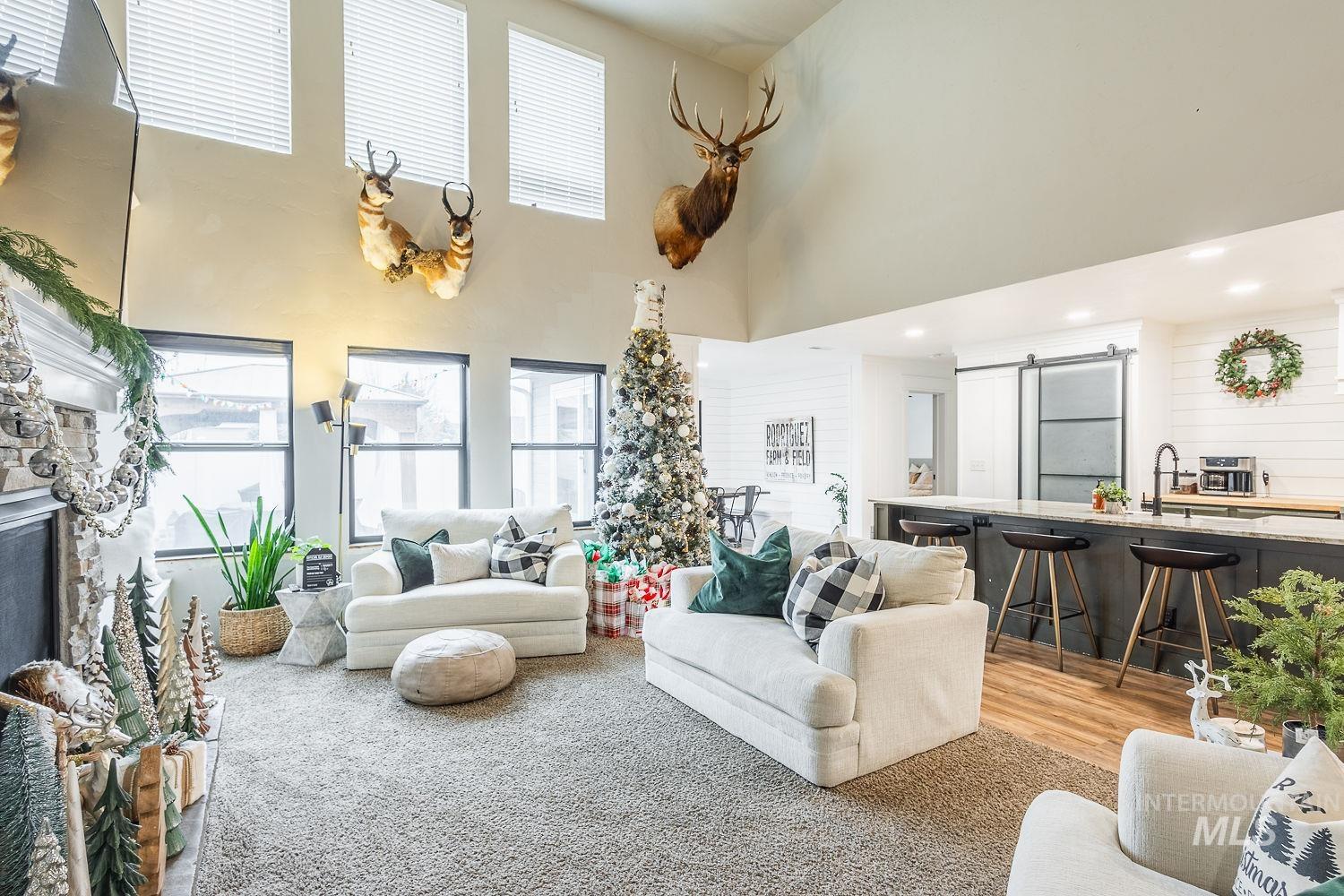 Living room featuring a barn door, a high ceiling, light wood-style flooring, and recessed lighting