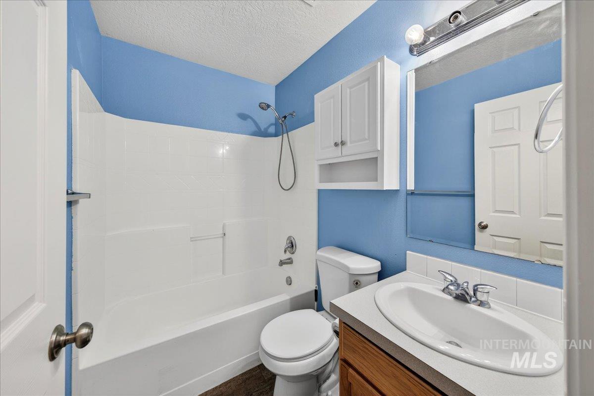 Full bathroom with a textured ceiling, vanity, and shower / bath combination