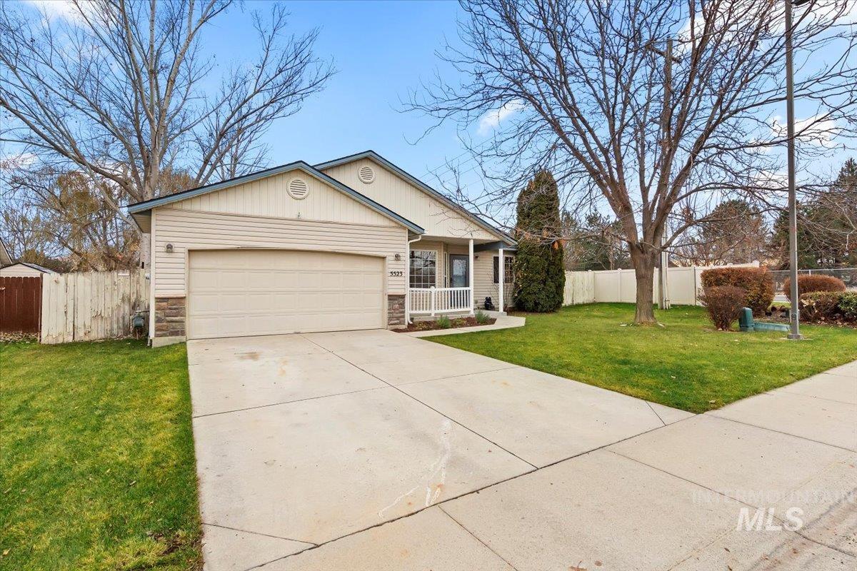 View of front of home with covered porch, stone siding, driveway, and an attached garage