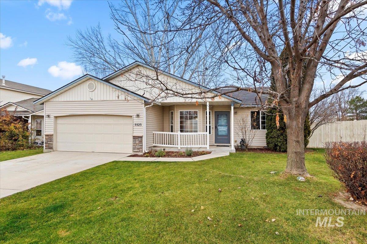 Single story home featuring driveway, stone siding, a garage, and covered porch